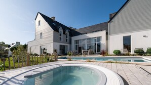 Une maison moderne dotée d’une piscine, d’un jacuzzi et d’un espace patio.