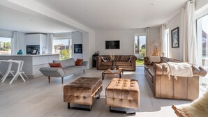 Un vaste espace de vie comprenant un canapé, des poufs et une table basse.