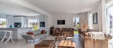 A spacious living area with a sofa, ottomans, and a coffee table.