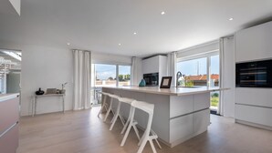 Une cuisine moderne dotée d’un îlot central, de tabourets de bar et de grandes fenêtres.