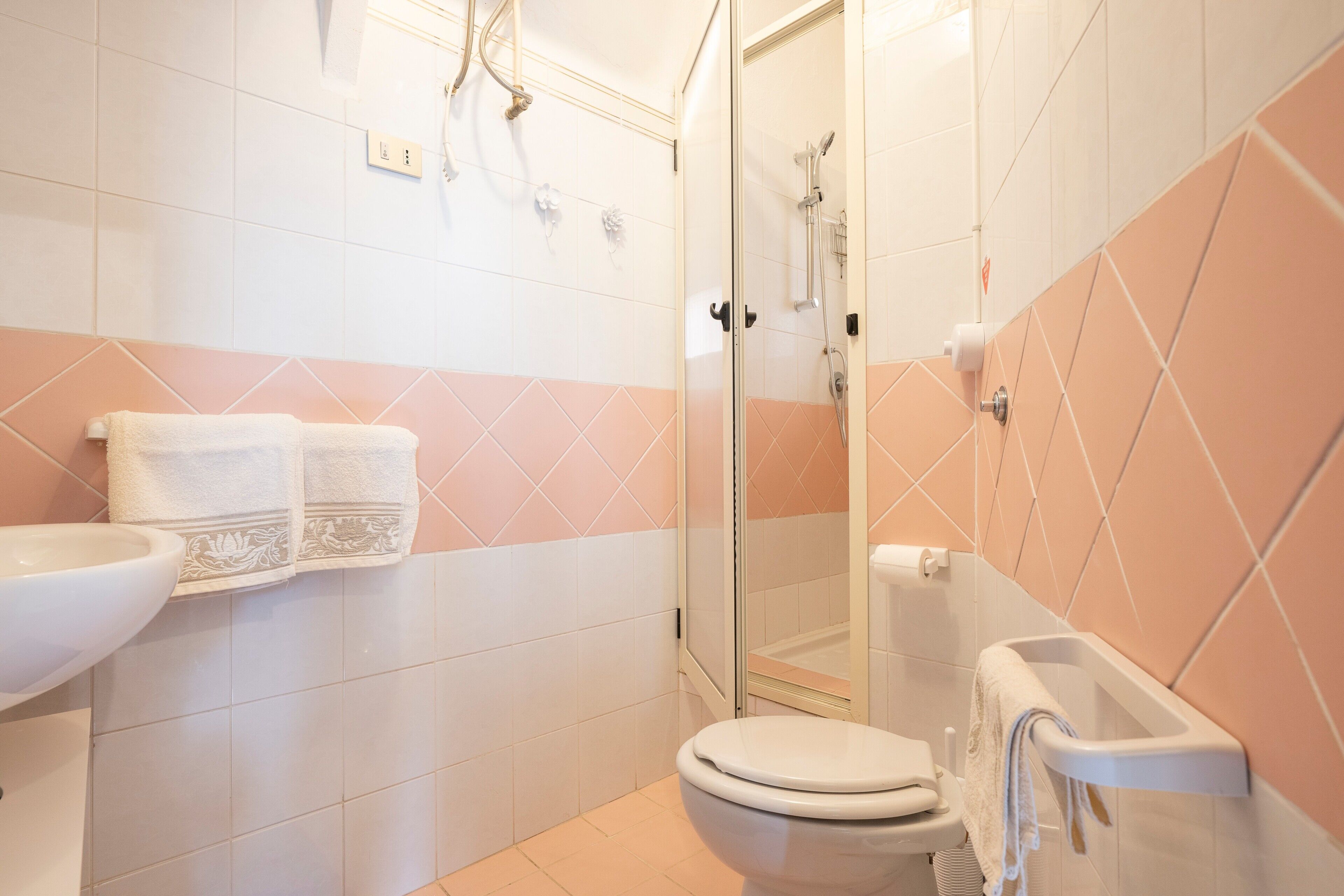 Ein Badezimmer mit Toilette, Waschbecken, Dusche und Handtuchhalter.