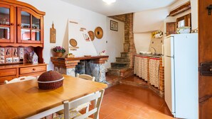 A kitchen with a wooden table, a refrigerator, and a brick fireplace.