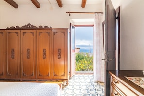 Une chambre dotée d’une grande armoire, d’un lit, d’une commode et d’un balcon avec vue.