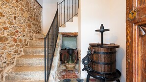 A stone staircase with a metal railing, a wooden barrel, and a rustic door.