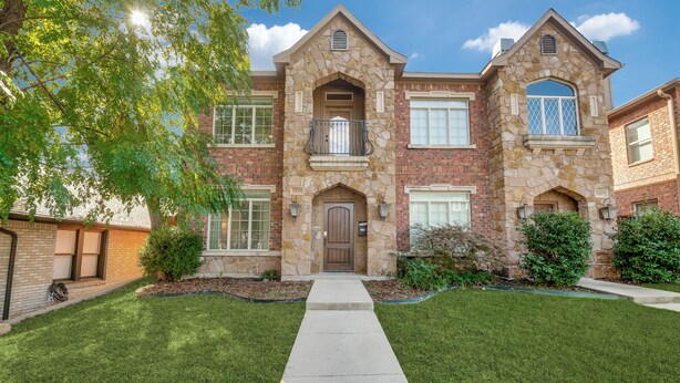A two-story house with a stone facade, a front entrance with a door, and a small balcony. - NEW! Charming Retreat Near Dickie's Arena – Cozy & Stylish Fort Worth Getaway (Fort Worth)