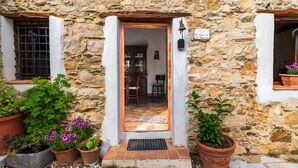 Un bâtiment en pierre avec une porte en bois, des plantes en pot et une enseigne indiquant qu’il s’agit d’un restaurant.