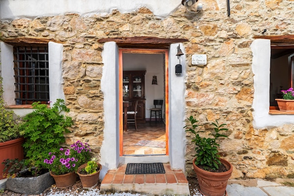 Un bâtiment en pierre avec une porte en bois, des plantes en pot et une enseigne indiquant qu’il s’agit d’un restaurant.