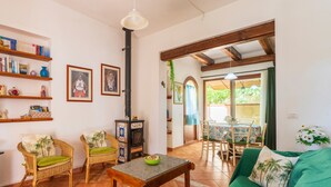 Een gezellige woonkamer met rieten meubels, een open haard en een eethoek met een tafel en stoelen.