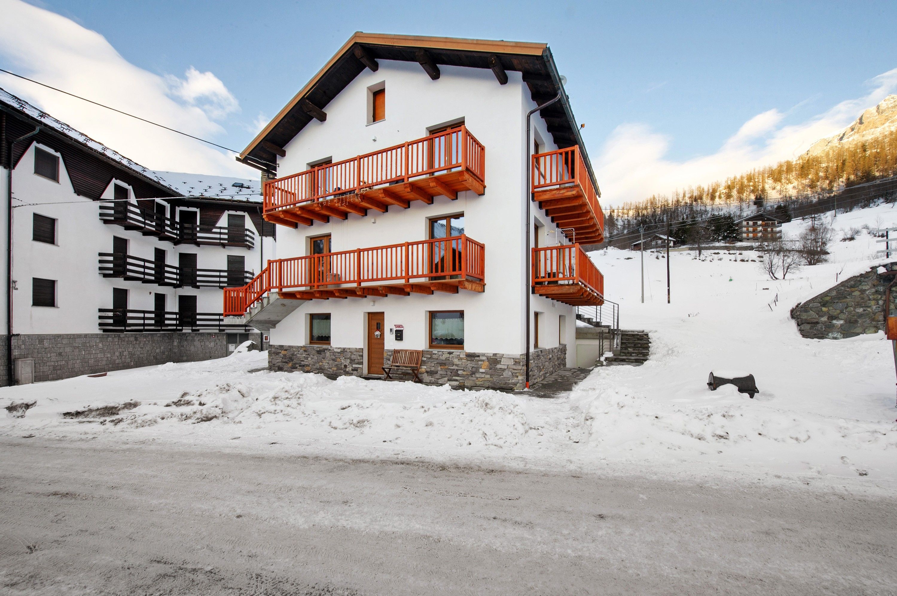 Un edificio de varios pisos con balcones, base de piedra y paisaje nevado.