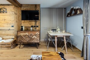 Una cocina moderna con un armario de madera en patrón de espiga, un televisor de pantalla plana y un comedor con mesa y sillas.