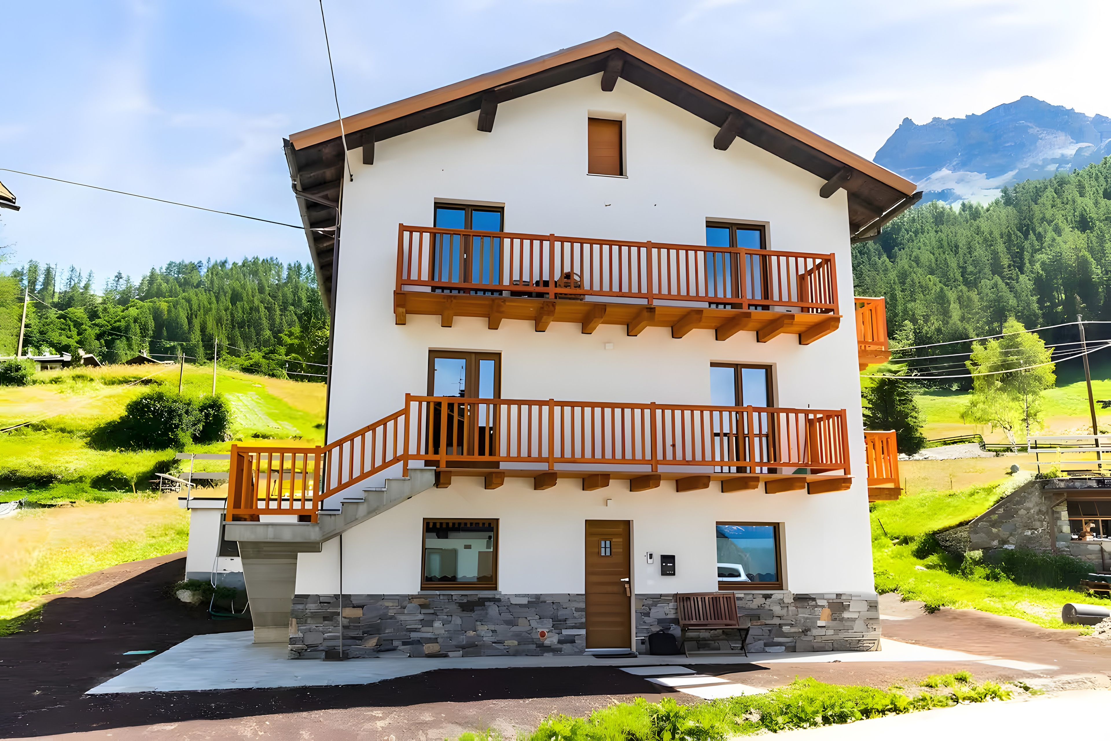 Un bâtiment à deux étages, doté de fondations en pierre, de balcons en bois et offrant une vue sur un paysage montagneux.