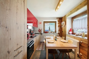 Une cuisine compacte avec des meubles en bois, une table à manger pour quatre personnes et une fenêtre donnant sur l’extérieur.