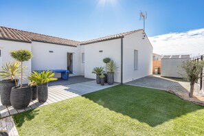 A modern house with a tiled roof, a small patio, and a well-maintained lawn.