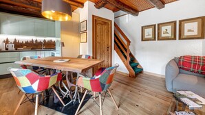 A wooden dining table with colorful chairs, a staircase, and framed pictures on the wall. - Chalet 'Nini's Home' with Terrace and Garden with BBQ (Schignano)