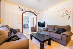 Ein Wohnzimmer mit zwei Sofas, einem Couchtisch, einem Fernseher und einer Wandverkleidung.