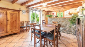 A wooden dining table with chairs, a stone wall, and a wooden cabinet.