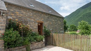 A stone building with a wooden door, surrounded by a gravel driveway and a wooden fence.