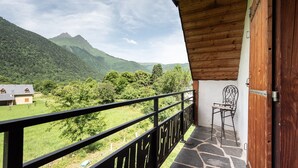 A balcony with a view of a mountain landscape, a chair, and a wooden door.