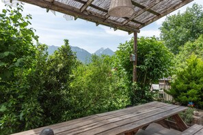 A wooden table under a pergola with a view of mountains.