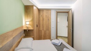 Habitación de hotel con cama, armario de madera, lámpara de noche y una puerta que da a otra habitación.