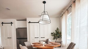 Een moderne keuken met witte kasten, een roestvrijstalen koelkast en een houten eettafel met vier stoelen.