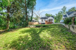 A residential property with a well-maintained lawn, a wooden deck, and a house with a dark roof.