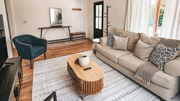 Een woonkamer met een bank, fauteuil, salontafel en een televisie.