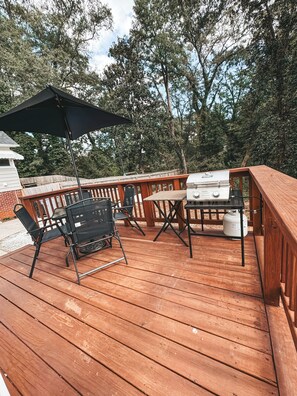 A wooden deck with a grill, chairs, and an umbrella. - Charming 2-bedroom house with WiFi, AC in Spartanburg (Spartanburg)