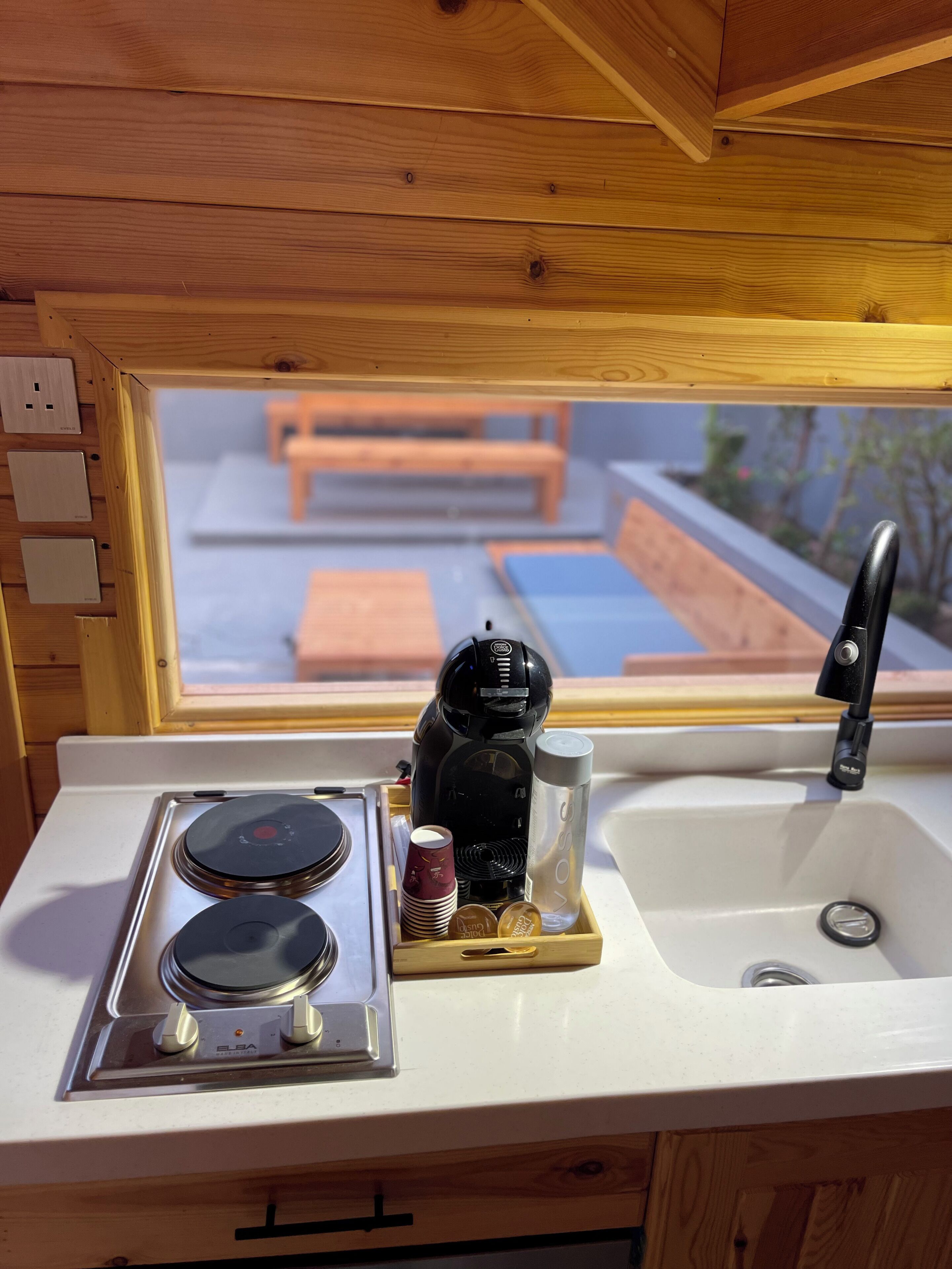 A kitchenette with a stove, coffee maker, and sink.