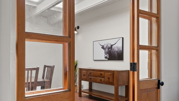 A wooden door with glass panels leading to a room with a brick floor, a wooden bench, and a framed picture on the wall. - Updated Spacious 4-bedroom house near Nob Hill and UNM.  (Albuquerque)