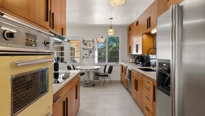 A modern kitchen with wooden cabinets, stainless steel appliances, and a dining area with a round table and chairs. - Updated Spacious 4-bedroom house near Nob Hill and UNM.  (Albuquerque)