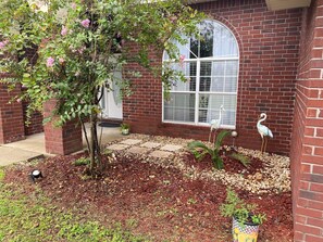 Stroll through the beautifully landscaped garden, featuring a variety of plants and a charming bird statue.