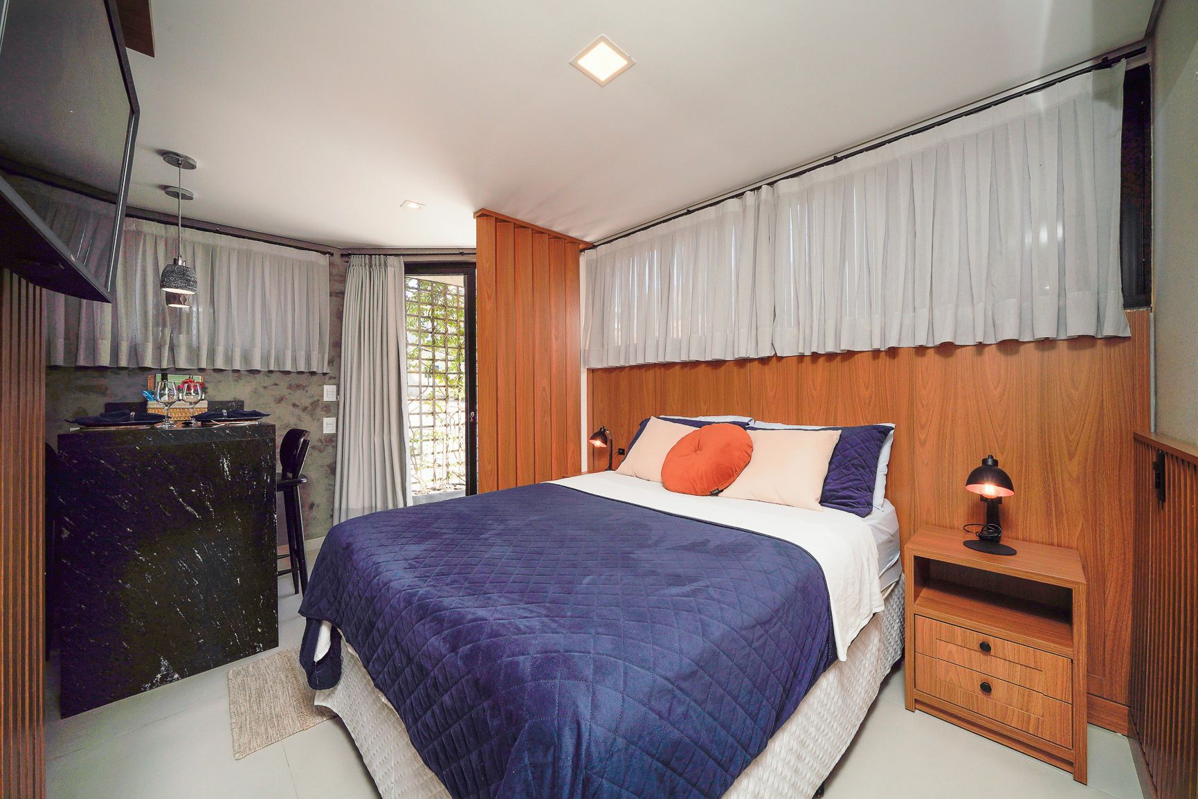 Une chambre à coucher avec un lit, une table de chevet, une lampe et un bureau avec une chaise.