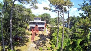 Ein Haus, umgeben von Bäumen, mit einer Treppe, die zum Eingang führt.