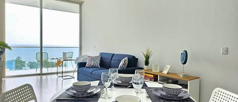 Un moderno comedor con una mesa redonda preparada para cuatro personas, con vajilla blanca y azul estampada.
