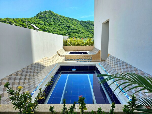A swimming pool with a geometric tile pattern, surrounded by a low wall and a planter with greenery. - Apartamento en Pozos Colorados  (Santa Marta)
