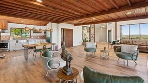 A spacious living area with wooden flooring, a dining table, and modern furniture. - Los Sueños Ranch Elgin AZ  (Elgin)