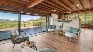 A spacious room with a high ceiling, large windows offering a view of the desert landscape, and a stone fireplace. - Los Sueños Ranch Elgin AZ  (Elgin)