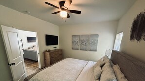 A bedroom with a bed, a dresser, a television, and artwork on the wall. - Cozy Cabin in Lake Community (Tallassee)