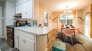 Una cocina con armarios blancos, una isla central y una zona de comedor con una mesa y sillas.