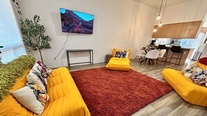 Ein modernes Wohnzimmer mit gelben Sofas, einem roten Teppich und einem an der Wand montierten Fernseher.
