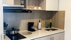 Cozinha moderna com fogão por indução preto, cafeteira, pia e armários de madeira.