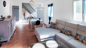 Ein geräumiger Wohnbereich mit einer Couch, einem Esstisch und einer Küchenzeile mit einer Treppe.