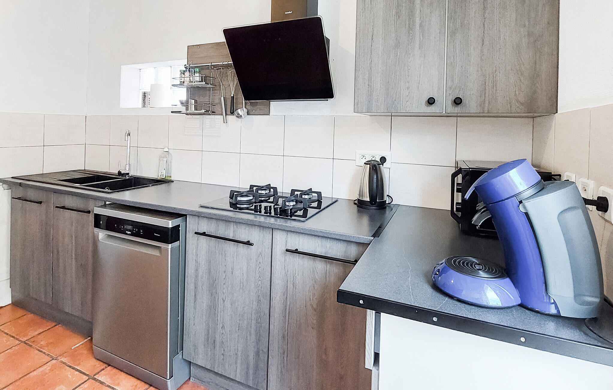 A modern kitchen with stainless steel appliances, a built-in dishwasher, and a coffee machine.