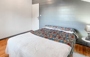 Een slaapkamer met een bed, een nachtkastje met lamp en een deur.