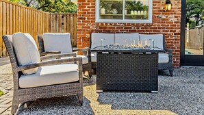 A patio with wicker furniture, a fire feature, and a brick wall.