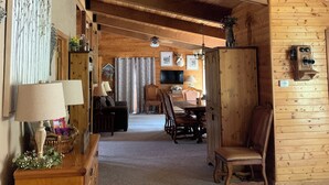A wooden interior with a dining area, a TV mounted on the wall, and a ceiling fan.