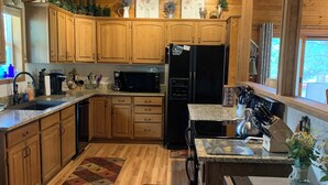 A wooden cabin-style kitchen with wooden cabinets, a refrigerator, a microwave, and a sink.
