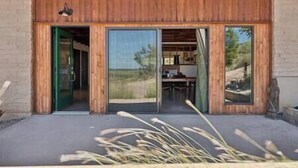 A modern building with large sliding glass doors, a wooden ceiling, and a view of the interior through the glass.