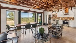 A spacious room with a high ceiling, a dining area with a table and chairs, a sofa, and a kitchen area with modern appliances.